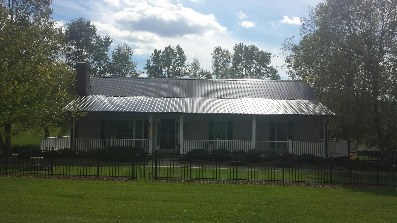 Gray metal roof on a brick ranch with a full width front porch — Gutter Guard Installation work by our crew in Natural Bridge Station