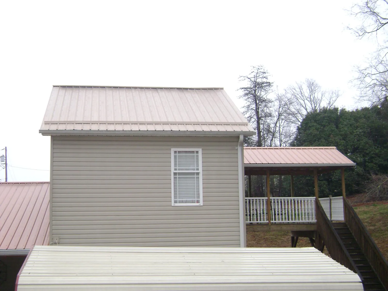 Tan metal roofs on a two story addition and attached porch, from a Roof Replacement job in Natural Bridge Station