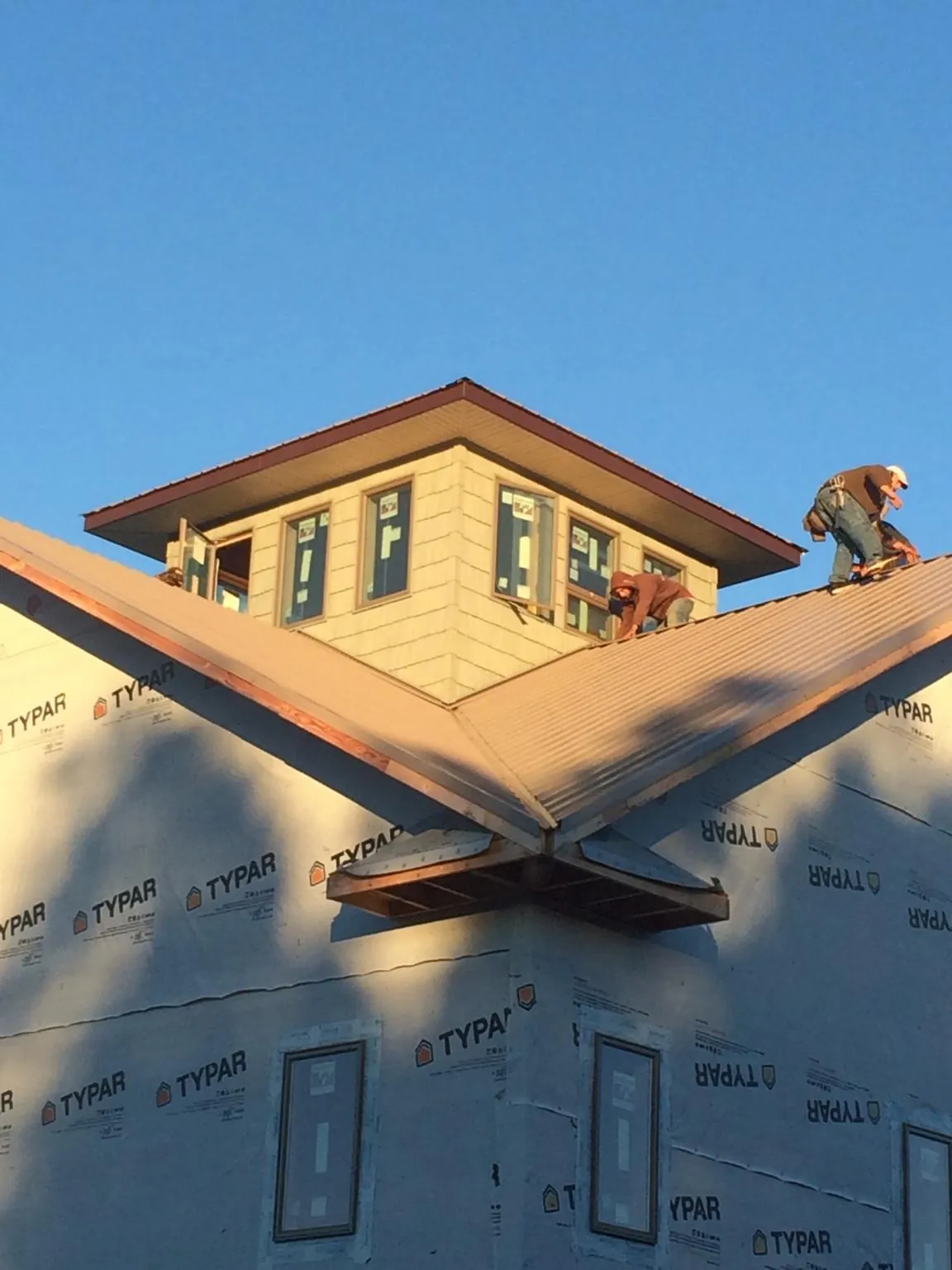 Roofers working around a rooftop cupola on a new metal roof at sunset — Roof Waterproofing in Natural Bridge Station by Roofing Brothers